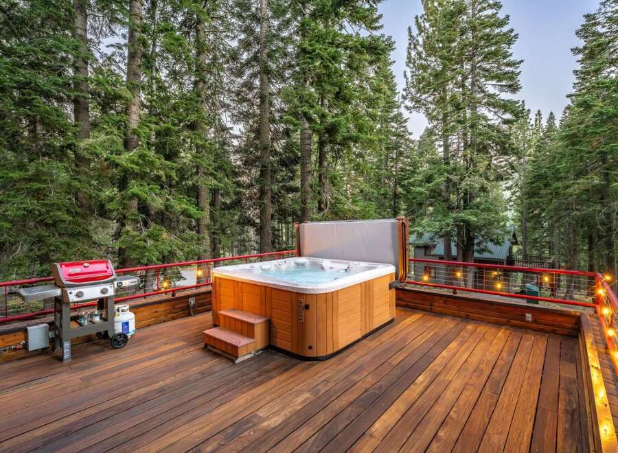 Experience ultimate relaxation on this spacious wooden deck, featuring a luxurious hot tub perfect for unwinding amidst the serene forest.
