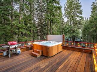 Experience ultimate relaxation on this spacious wooden deck, featuring a luxurious hot tub perfect for unwinding amidst the serene forest.