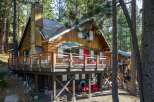 Nestled among tall pine trees, this charming wooden cabin offers a rustic retreat with a spacious deck perfect for outdoor entertaining.