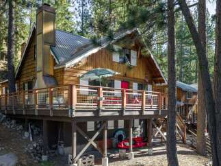 Nestled among tall pine trees, this charming wooden cabin offers a rustic retreat with a spacious deck perfect for outdoor entertaining.