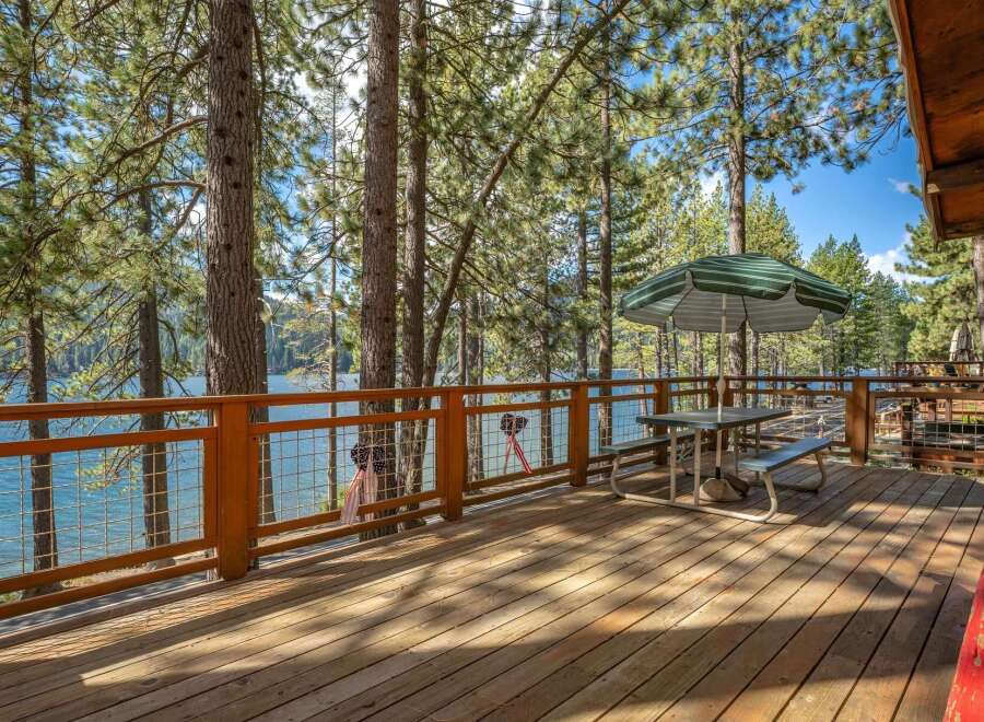 Enjoy breathtaking lake views from this expansive wooden deck, perfect for outdoor dining and relaxation.