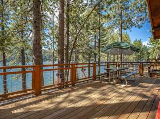 Enjoy breathtaking lake views from this expansive wooden deck, perfect for outdoor dining and relaxation.