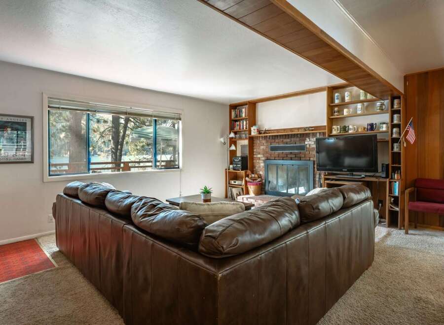 Cozy up by the brick fireplace in this inviting living room, featuring a spacious sectional sofa perfect for family gatherings.