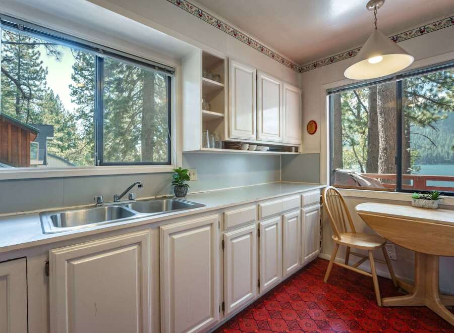 Enjoy breathtaking lake and mountain views from this charming kitchen, featuring a double sink and ample cabinet space.