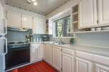 This charming kitchen features crisp white cabinetry and a classic floral wallpaper border, creating a bright and inviting atmosphere.