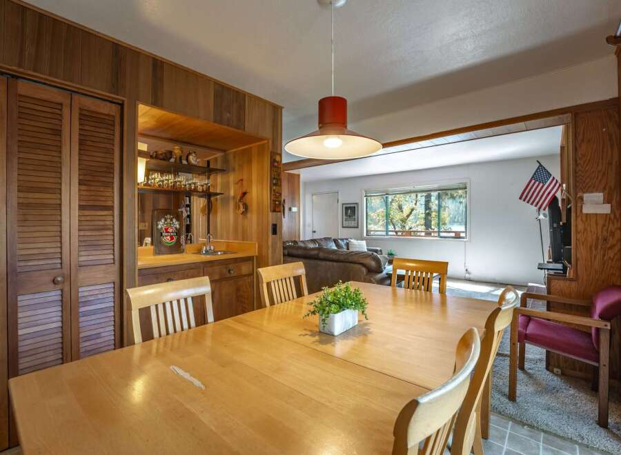 This charming dining area features a large wooden table perfect for family gatherings, complemented by a built-in bar with ample shelving for glassware.