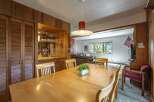 This charming dining area features a large wooden table perfect for family gatherings, complemented by a built-in bar with ample shelving for glassware.