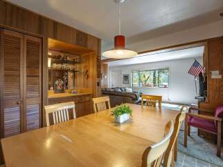 This charming dining area features a large wooden table perfect for family gatherings, complemented by a built-in bar with ample shelving for glassware.