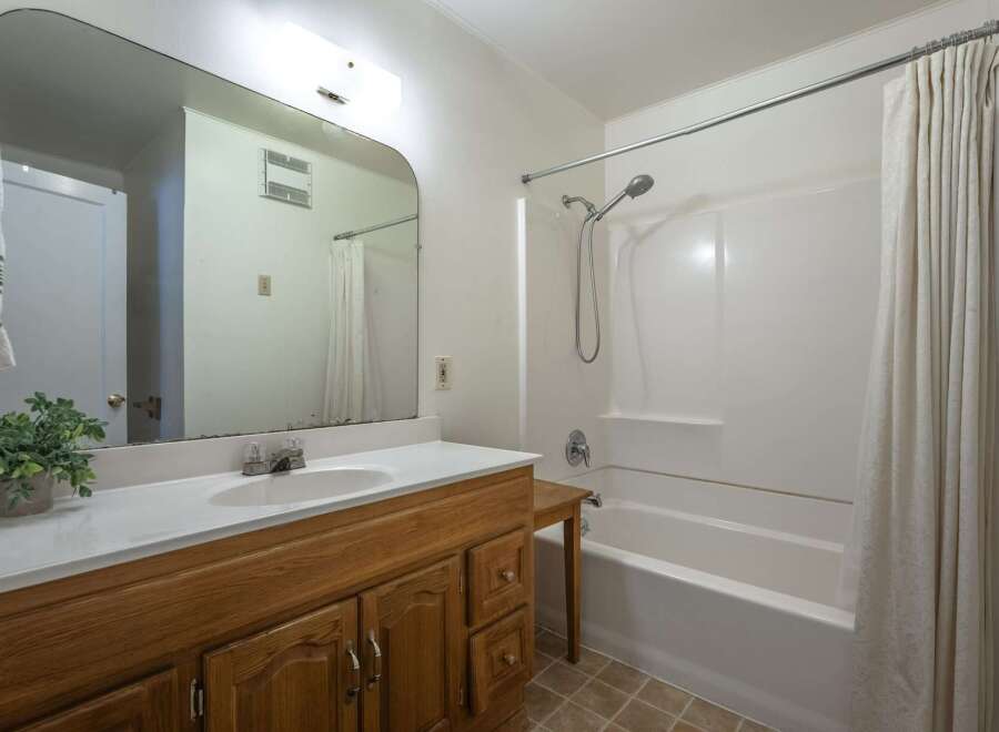 This bathroom features a spacious vanity with ample storage and a large mirror, perfect for your morning routine.