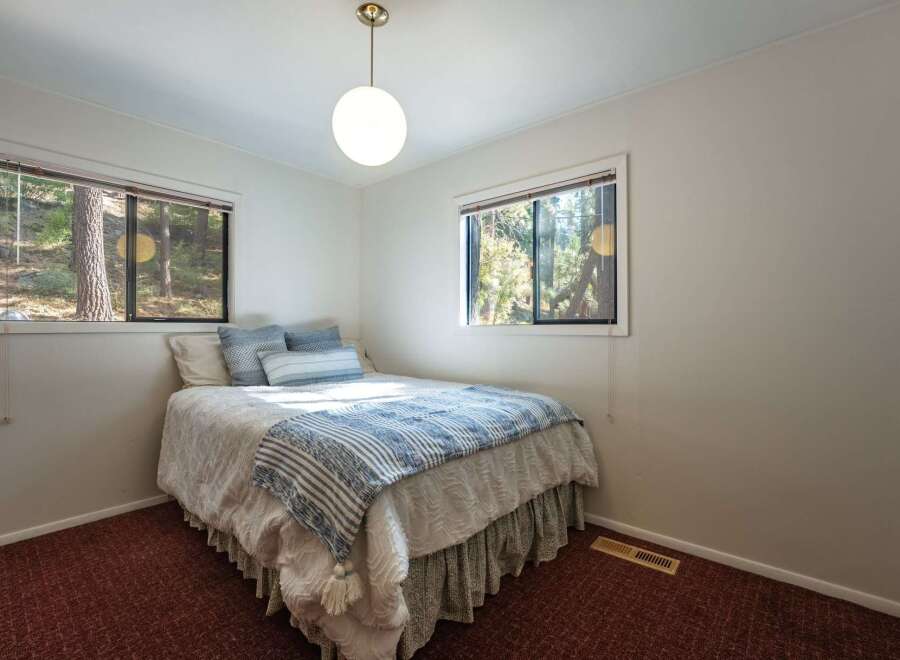 This charming bedroom offers a cozy retreat with its comfortable queen-size bed, adorned with blue and white striped bedding and plush pillows.