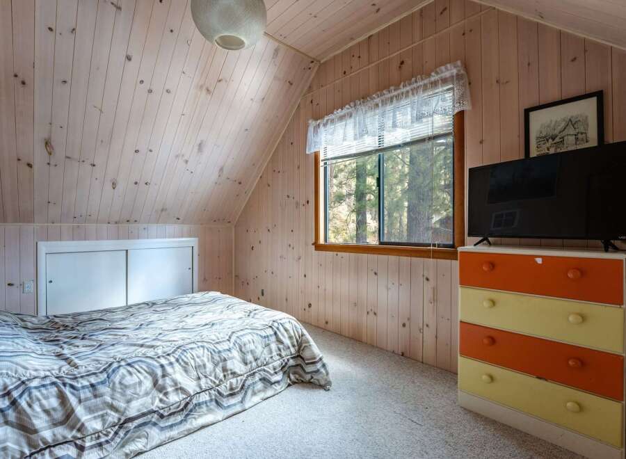Cozy attic bedroom featuring a comfortable bed with a patterned comforter and a sliding door closet.