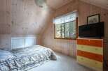 Cozy attic bedroom featuring a comfortable bed with a patterned comforter and a sliding door closet.