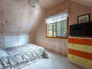 Cozy attic bedroom featuring a comfortable bed with a patterned comforter and a sliding door closet.