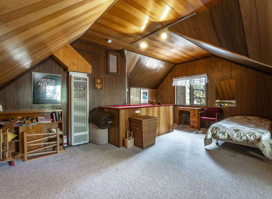 Discover this charming attic bedroom, featuring a cozy sleeping area and a dedicated workspace with a desk and chair.