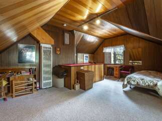 Discover this charming attic bedroom, featuring a cozy sleeping area and a dedicated workspace with a desk and chair.