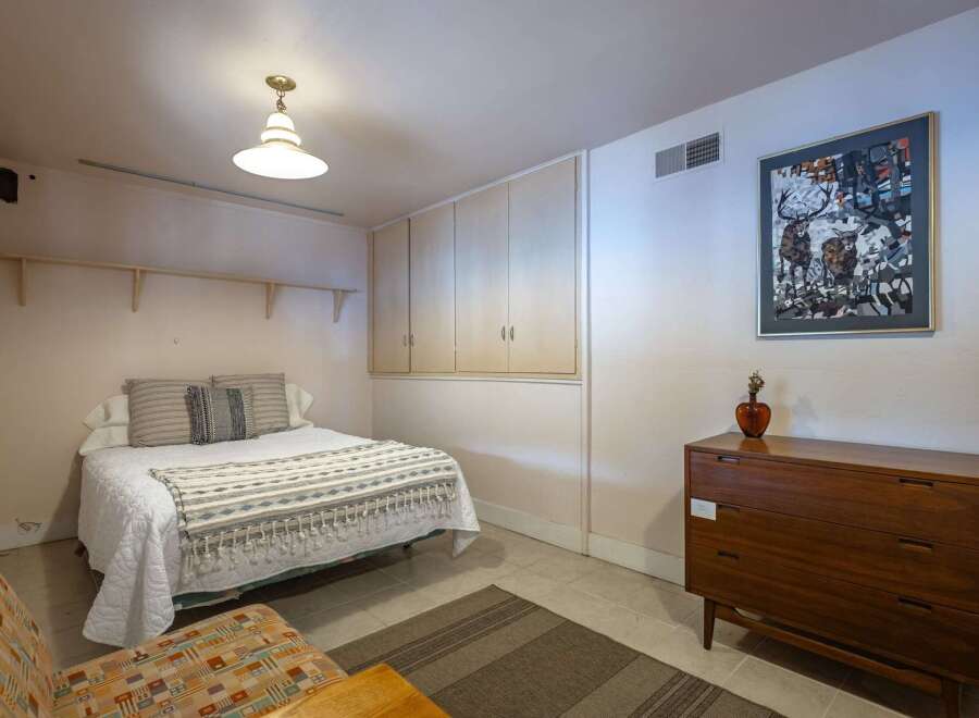 Discover this charming bedroom featuring a comfortable queen-size bed adorned with a decorative throw and plush pillows.