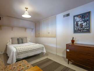Discover this charming bedroom featuring a comfortable queen-size bed adorned with a decorative throw and plush pillows.