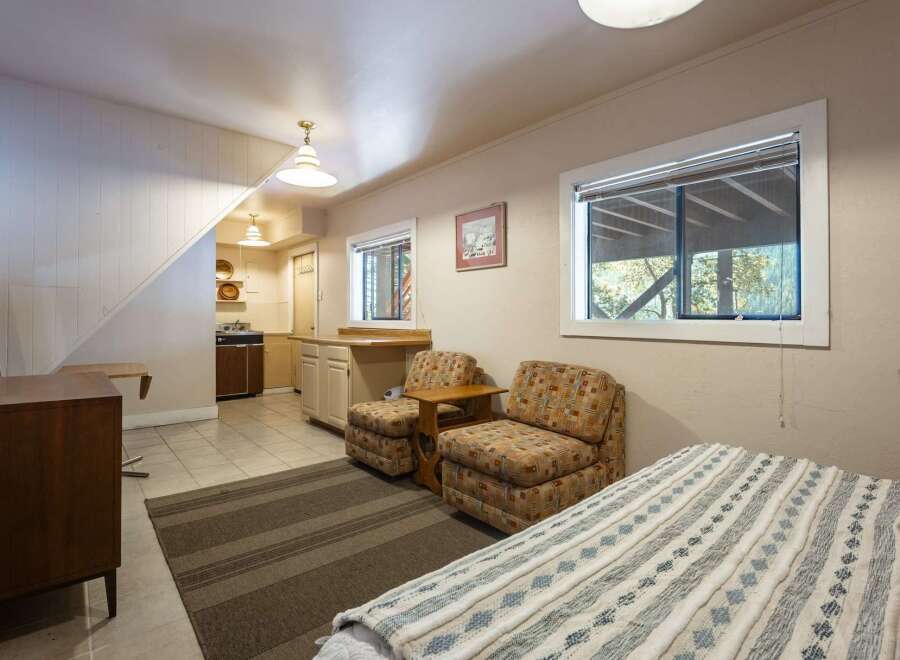 Discover this charming studio apartment featuring a compact kitchen area and a cozy living space with two accent chairs.