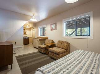 Discover this charming studio apartment featuring a compact kitchen area and a cozy living space with two accent chairs.
