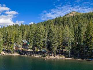 Experience lakeside living at its finest with this stunning property nestled among towering pine trees.