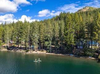 Experience lakeside living at its finest with this stunning property nestled among tall pine trees.