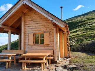 Discover this charming wooden cabin nestled on a lush green mountainside, offering breathtaking views and a serene escape.
