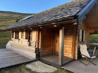 Experience rustic charm in this wooden cabin, featuring a durable shingle roof and a welcoming wooden deck.