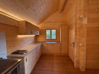 Experience rustic charm in this beautifully crafted wooden kitchen, featuring warm pine cabinetry and a sleek gas stovetop.