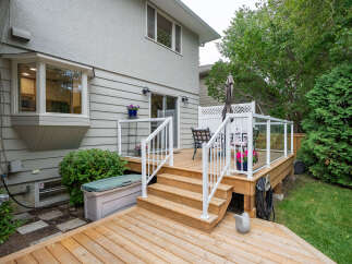 Enjoy outdoor living on this beautiful wooden deck, complete with glass railings and comfortable seating.