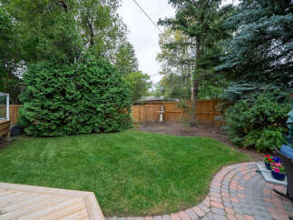 Enjoy outdoor living in this beautifully landscaped backyard, featuring a spacious green lawn perfect for recreation and relaxation.