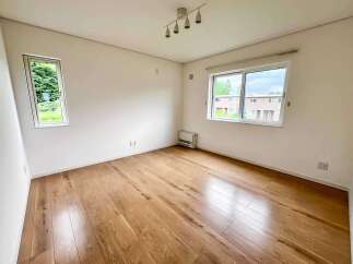 This bright and airy room features beautiful hardwood floors that gleam under the natural light pouring in from two large windows.