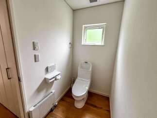 Discover this modern and clean bathroom featuring a sleek white toilet with advanced bidet functions and a convenient dual-roll toilet paper holder.