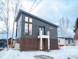 Discover modern living in this striking dark-clad home, featuring a unique asymmetrical roofline and large, expansive windows that invite natural light.
