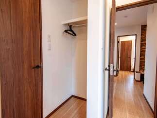 Step into a welcoming entryway featuring a sleek wooden door and a convenient built-in closet with hangers.