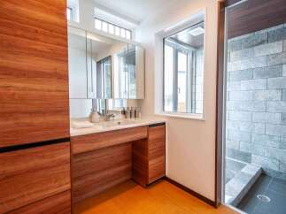 Experience modern luxury in this bathroom featuring a sleek wooden vanity with ample storage and a pristine white countertop.