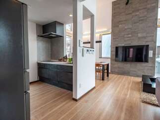 Experience modern living in this open-concept home featuring a sleek, contemporary kitchen with dark cabinetry and a stylish stone accent wall in the living area.