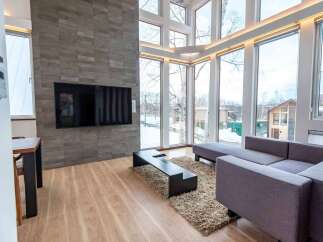 Experience modern living in this stunning home featuring a spacious living area with a large, stone-accented wall and a sleek flat-screen TV.