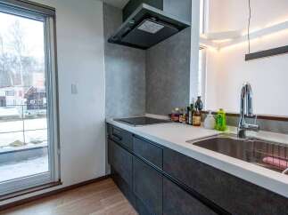Experience modern living in this sleek kitchen featuring a built-in induction cooktop and a stylish range hood.