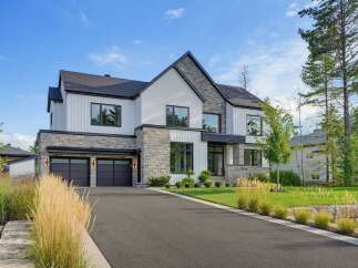 Experience modern luxury in this stunning architectural masterpiece, featuring a striking facade of white vertical siding and natural stone accents.