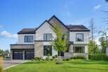 This modern luxury home boasts a striking architectural design with a mix of stone and white siding.