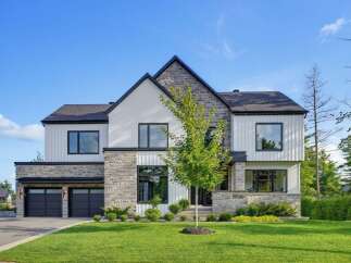 This modern luxury home boasts a striking architectural design with a mix of stone and white siding.