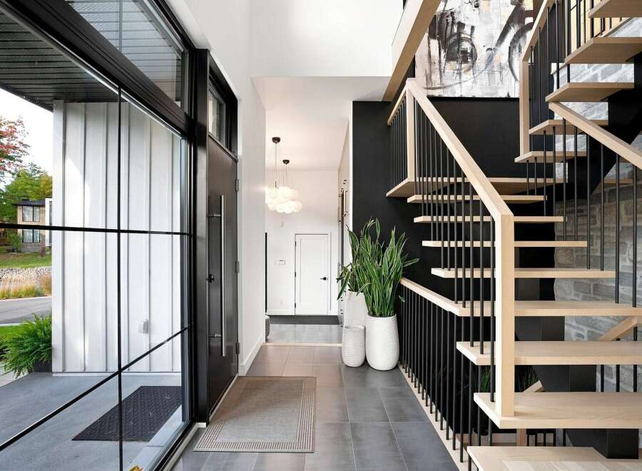 Step into a modern entryway featuring a sleek black door and expansive glass windows that flood the space with natural light.