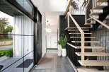 Step into a modern entryway featuring a sleek black door and expansive glass windows that flood the space with natural light.