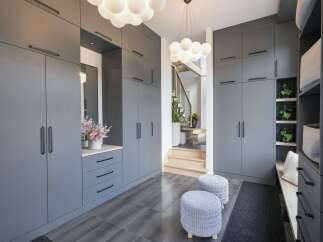 Step into a modern entryway featuring sleek, floor-to-ceiling grey cabinetry for ample storage.