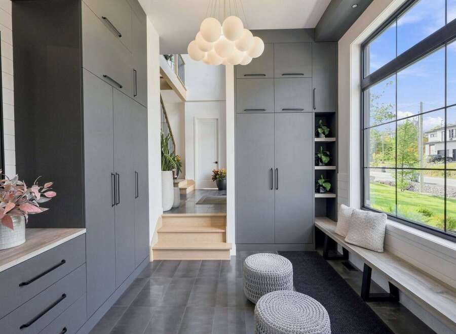 Step into a modern entryway featuring sleek grey cabinetry for ample storage and a stylish cloud-like chandelier.