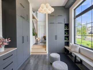 Step into a modern entryway featuring sleek grey cabinetry for ample storage and a stylish cloud-like chandelier.