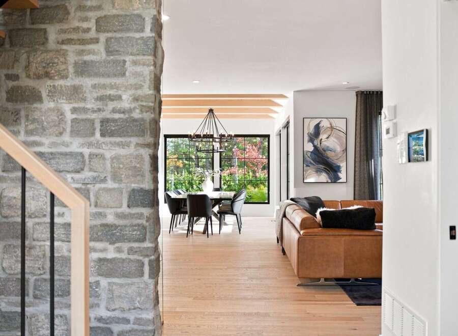 Step into a beautifully designed open-concept living space, featuring a modern dining area with a striking chandelier and large windows overlooking a vibrant garden.