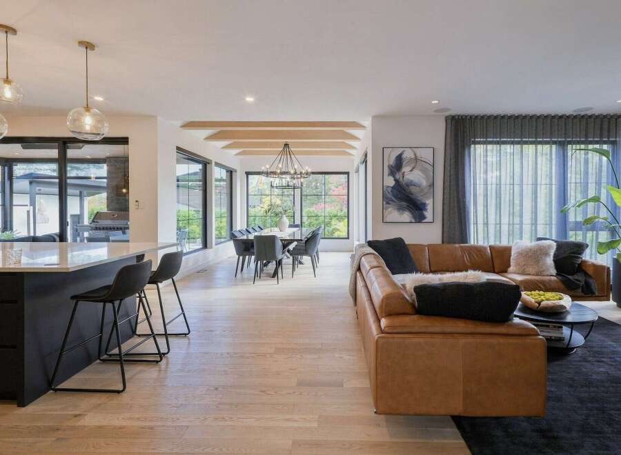Experience modern luxury in this open-concept living space, featuring a sleek kitchen island with bar stools and a sophisticated dining area.