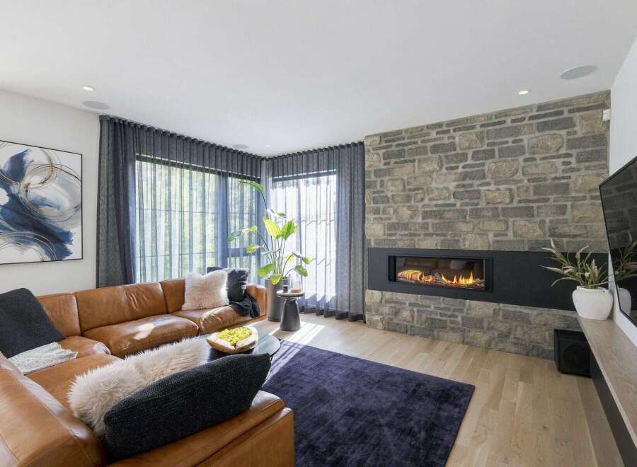 Experience modern luxury in this stunning living room, featuring a sleek gas fireplace set against a rustic stone accent wall.