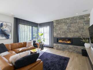 Experience modern luxury in this stunning living room, featuring a sleek gas fireplace set against a rustic stone accent wall.